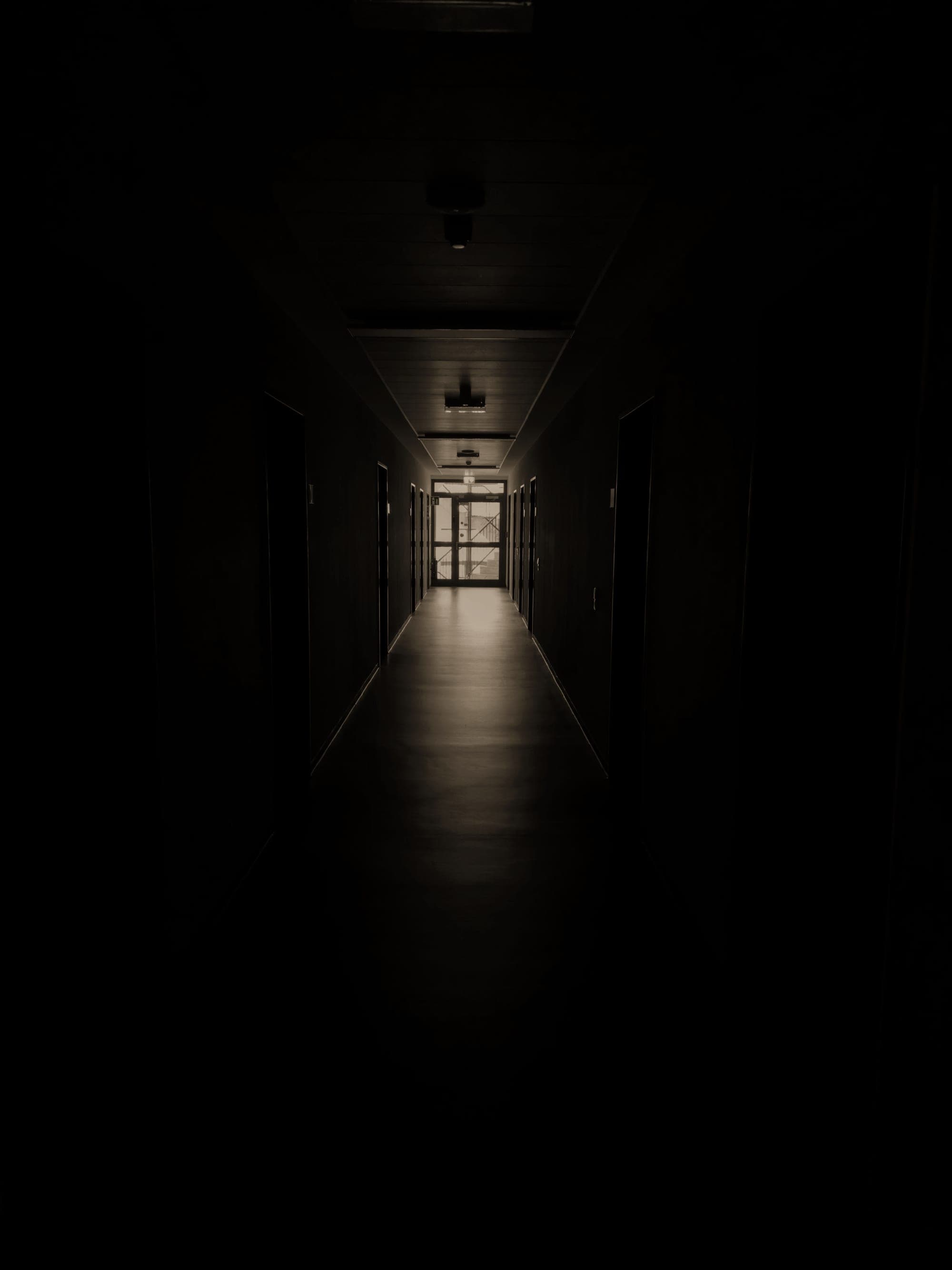A dim corridor leading to a lit doorway