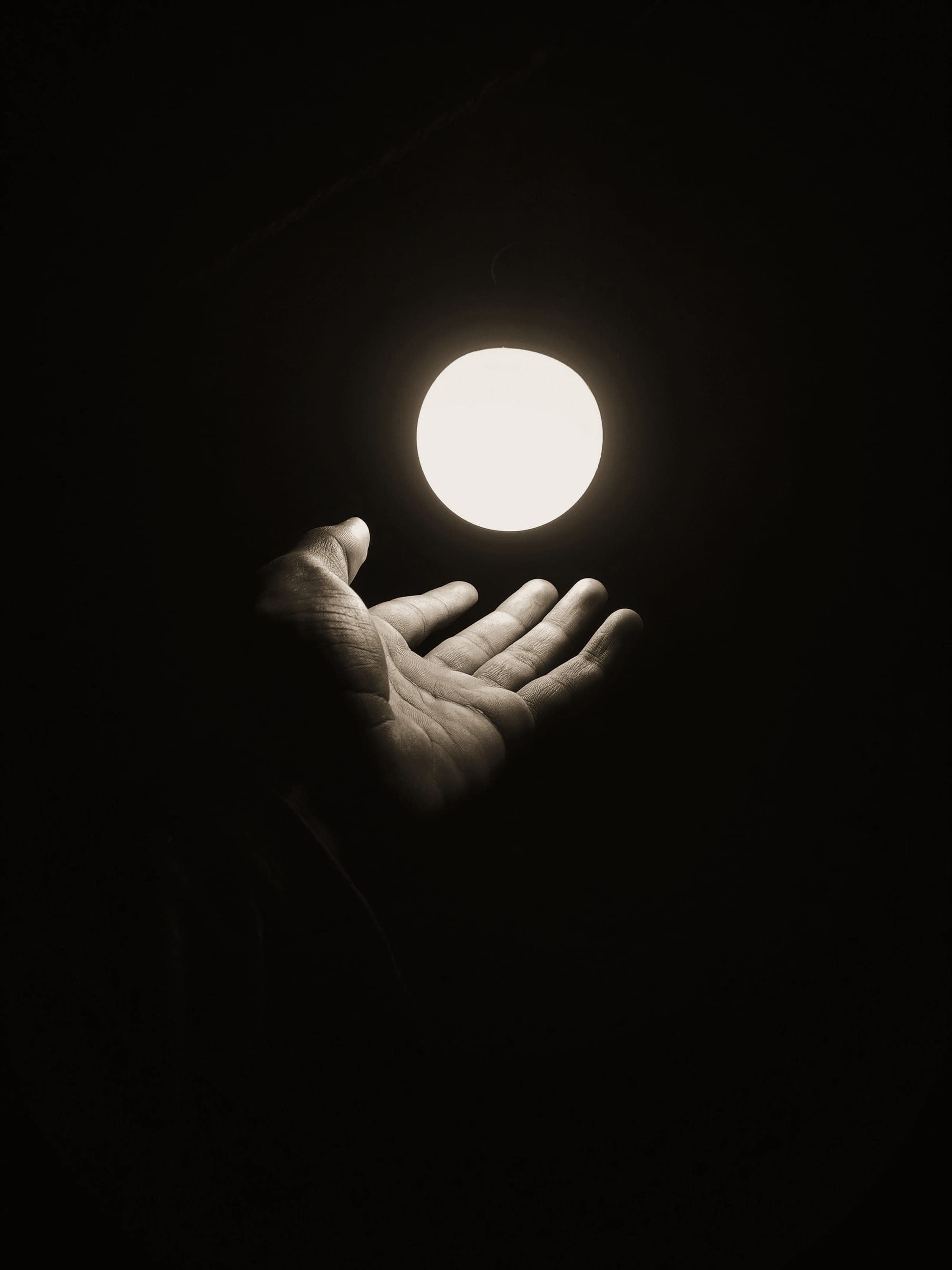 An open hand under a small sphere of light