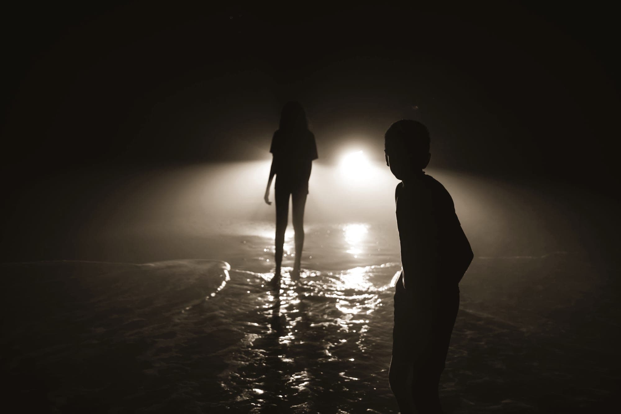 Two figures talking in mist, lit from behind